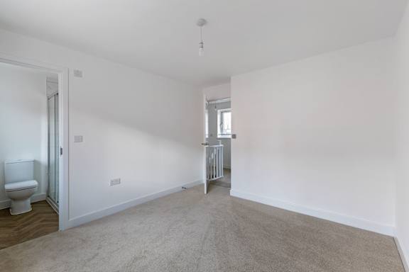 A white bathroom with a toilet and a carpeted floor.