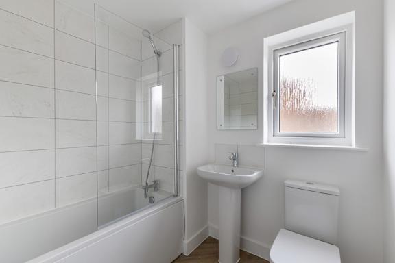 A white bathroom with a tub, sink, and toilet.