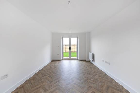 A room with a wooden floor and a door leading outside.