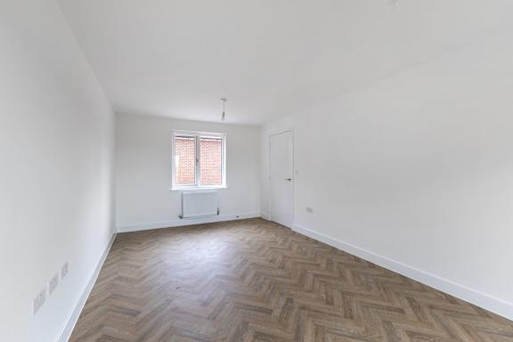 A room with wooden flooring and a window with blinds.