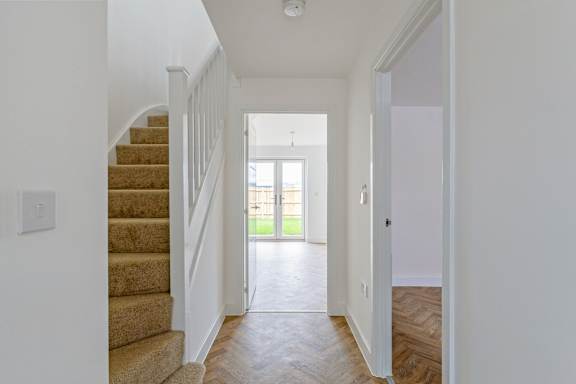 A hallway with a staircase leading to a door.