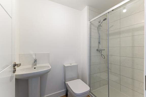 A white bathroom with a toilet, sink, and shower.