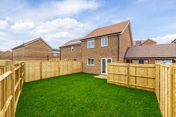 A backyard with a wooden fence and a green lawn.
