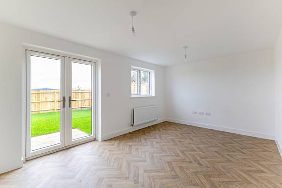 A room with a wooden floor and a window overlooking a backyard.