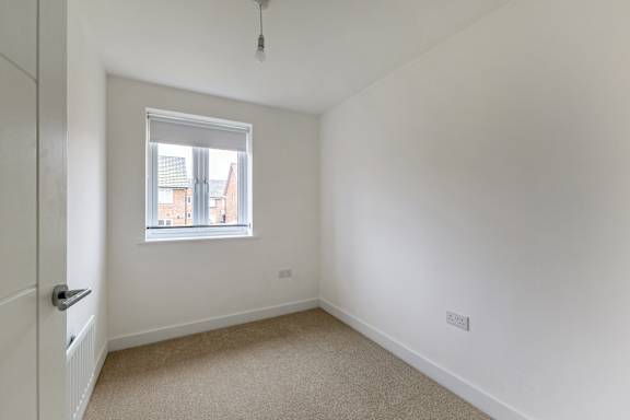 A white room with a window and a carpeted floor.