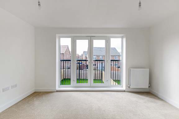 A white room with a large window and a radiator on the wall.