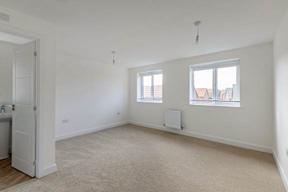 A white room with a carpeted floor and two windows.