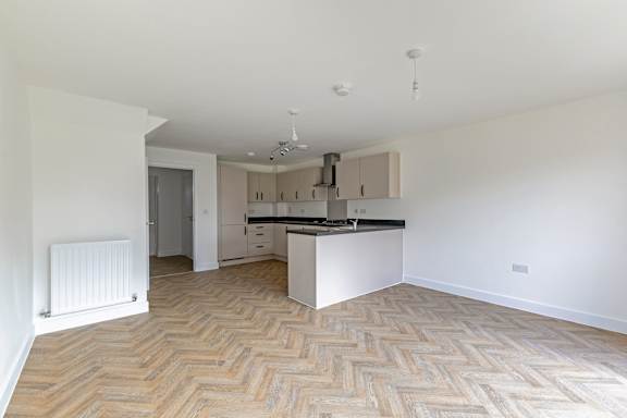 A kitchen with a white counter top and wooden flooring.