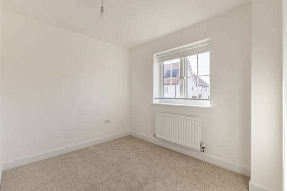 A room with a window and a radiator on the floor.