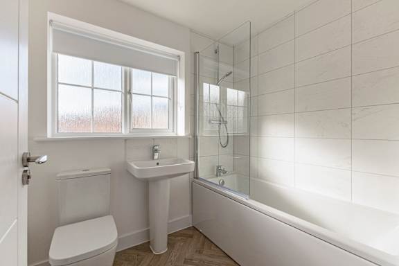 A white bathroom with a toilet, sink, and bathtub.