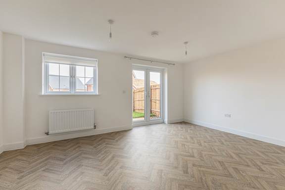 A room with a herringbone parquet floor and a white wall.