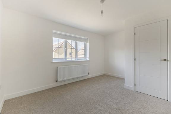 A room with a white door, a window with a white frame, and a white radiator.