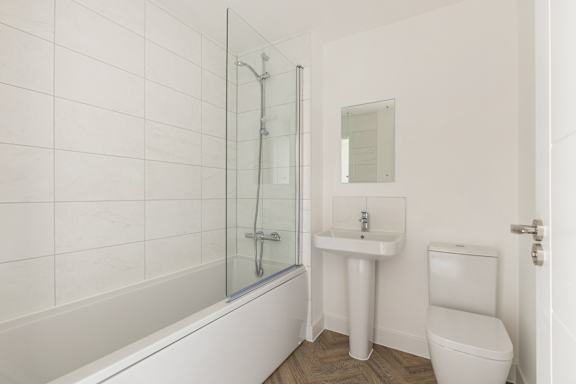 A white bathroom with a toilet, sink, and bathtub.