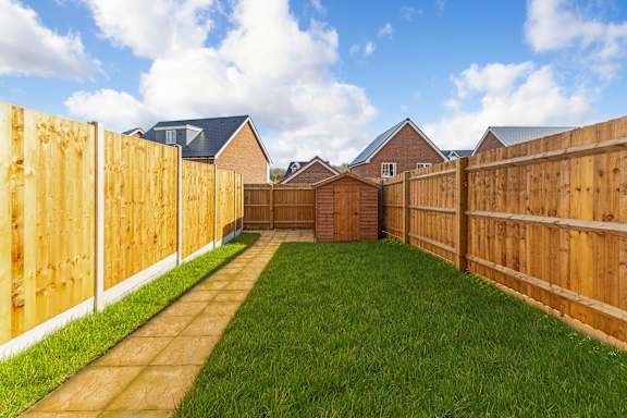 A backyard with a wooden fence and a green lawn.