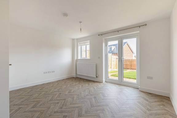 A room with a herringbone patterned floor and a sliding glass door.