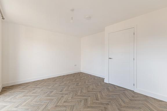 A room with a herringbone patterned floor and white walls.