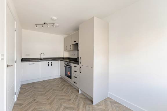 A kitchen with white cabinets and a black countertop.