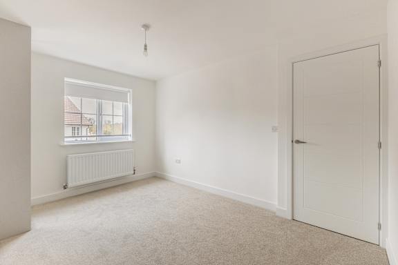 A room with a white door, a window with a white frame, and a white radiator.
