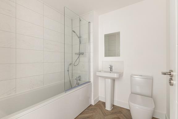 A white bathroom with a toilet, sink, and bathtub.