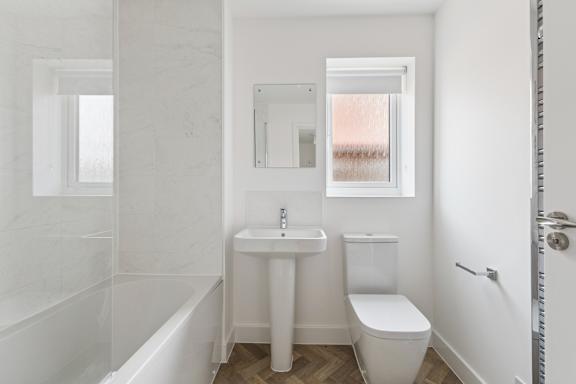A white bathroom with a tub, sink, and toilet.