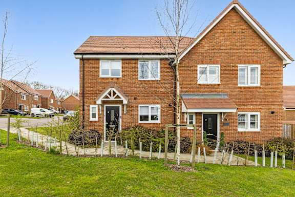 A red brick house with a white fence in front.