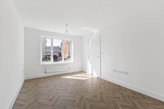 A room with a window and a wooden floor.
