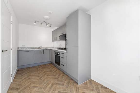 A kitchen with a wooden floor and white walls.