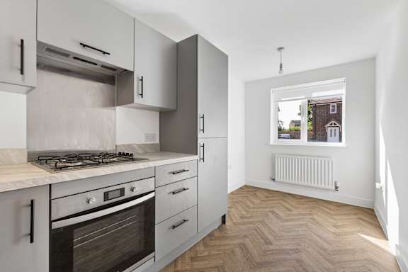 A kitchen with a stove top oven and a window.