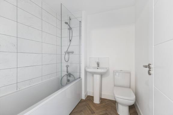 A white bathroom with a tub, toilet, and sink.