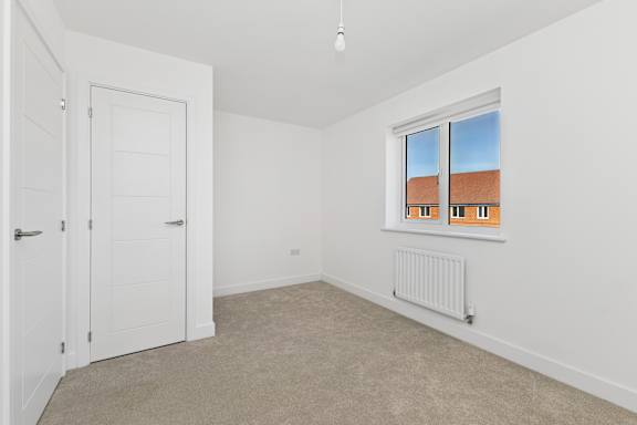 A room with a window showing a view of a building with orange roofs.