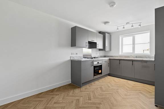 A kitchen with wooden flooring and a grey cabinetry.