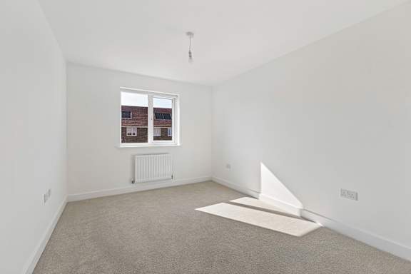 A white room with a window and a white sailboat on the floor.