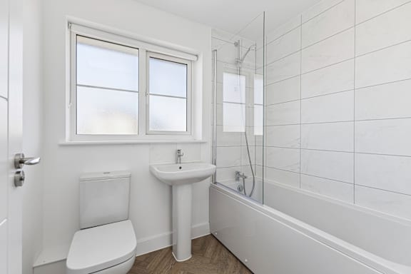 A white bathroom with a toilet, sink, and bathtub.