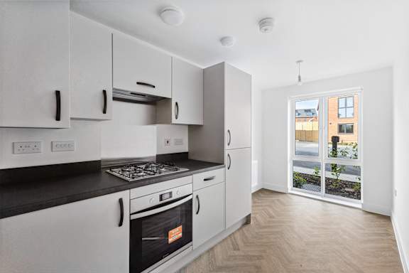 A kitchen with white cabinets and a black countertop.