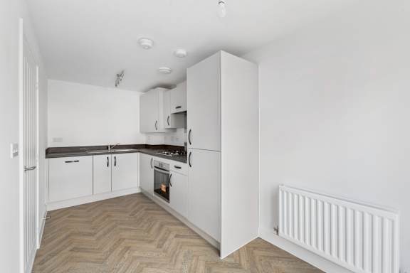 A white kitchen with a wooden floor and white walls.
