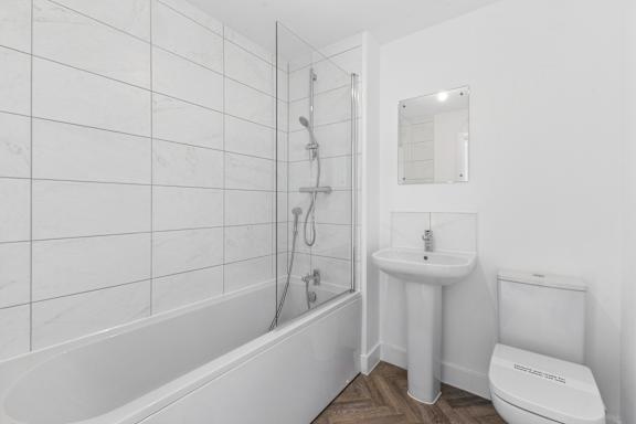 A white bathroom with a tub, sink, and toilet.