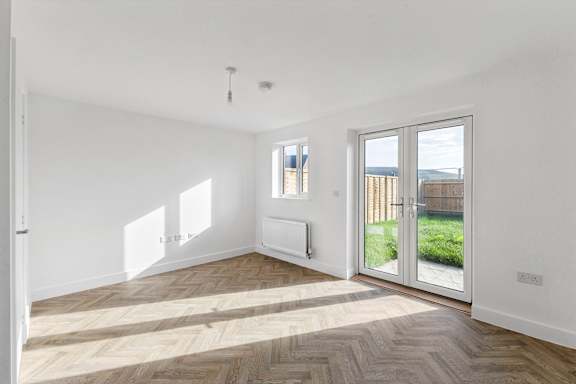 A room with a wooden floor and a sliding glass door leading to a backyard.