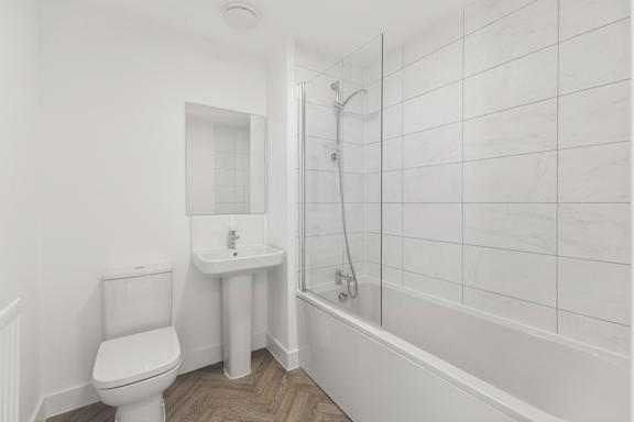 A white bathroom with a toilet, sink, and bathtub.
