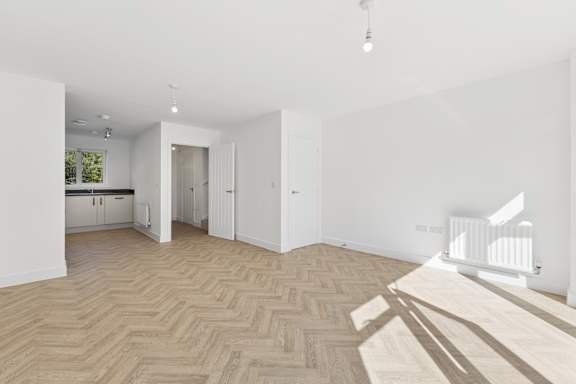 A room with a herringbone patterned floor and white walls.