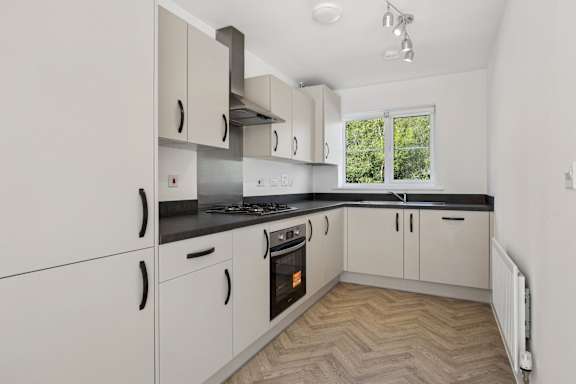 A kitchen with white cabinets and a black countertop.
