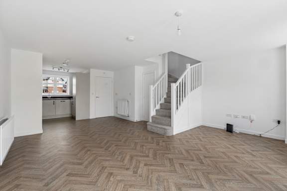 A spacious room with a wooden floor and a staircase.
