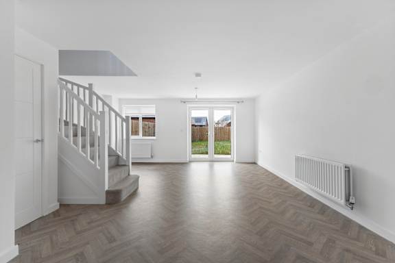 A room with a wooden floor and a staircase.
