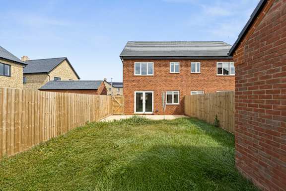 A backyard with a wooden fence and a brick house.
