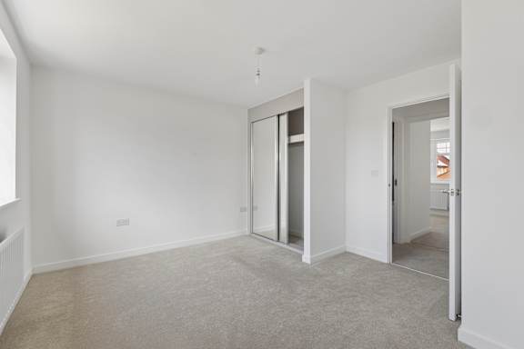 A white room with a carpeted floor and a doorway leading to another room.