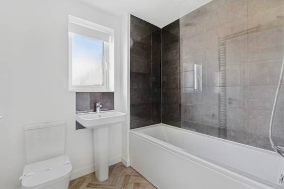 A white bathroom with a toilet, sink, and bathtub.