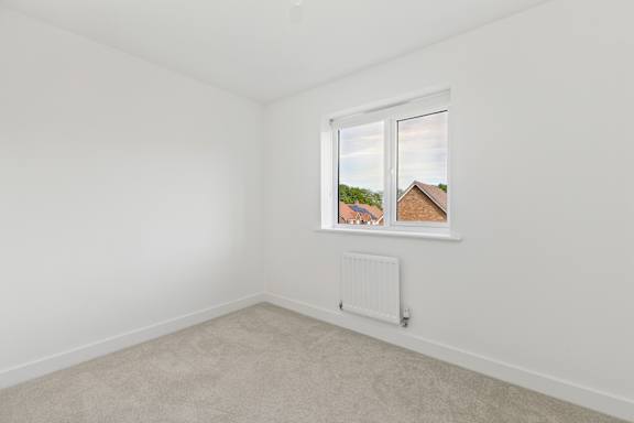 A room with a window showing a view of a house across the way.