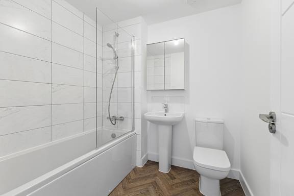 A white bathroom with a tub, sink, and toilet.