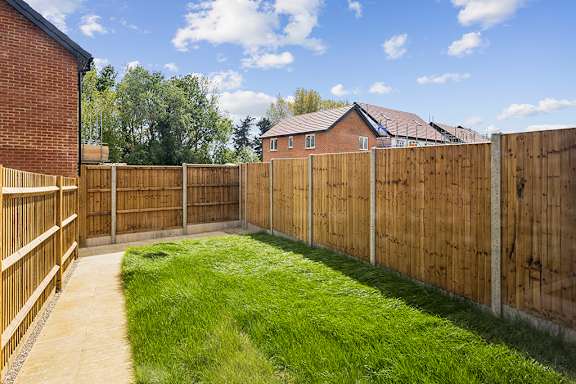 A backyard with a wooden fence and a green lawn.