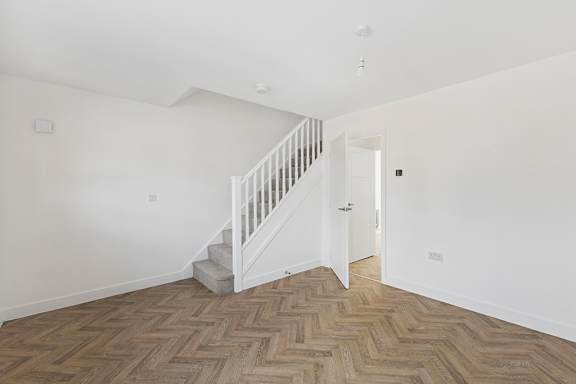 A room with a wooden floor and a staircase.