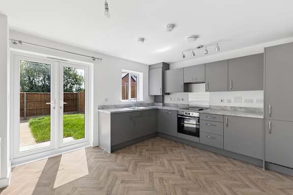 A kitchen with a white counter top and grey cabinets.
